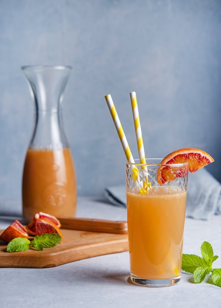 Sweet orange juice with a slice of red orange and mint on a gray background