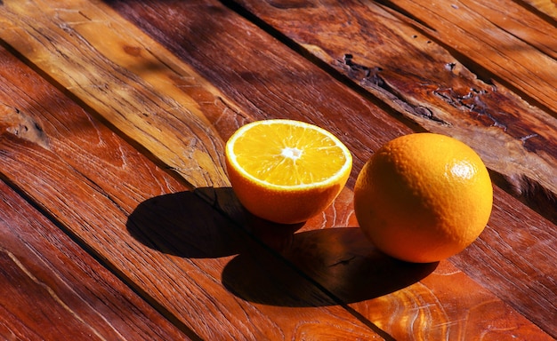 Foto arance dolci e la sua ombra sul tavolo in legno di teak