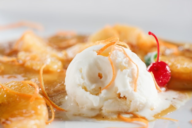 Sweet pancake with ice cream closeup. Homemade dessert with orange sauce on white plate.