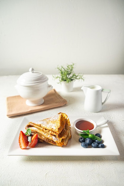 Sweet pancakes with berries and honey on a white plate selective focus