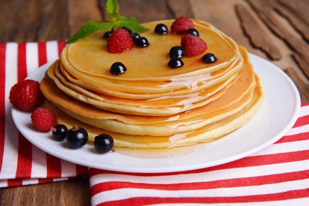 Sweet pancakes with berries on table closeup