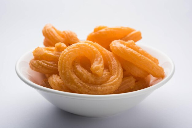 Сладкий Paneer Jalebi подается в керамической тарелке на красочном или деревянном фоне. Выборочный фокус