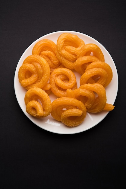 Photo sweet paneer jalebi served in a ceramic plate over colourful or wooden background. selective focus