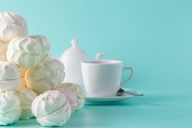 Sweet pastel colored marshmallow and cup of coffee on aquamarine background