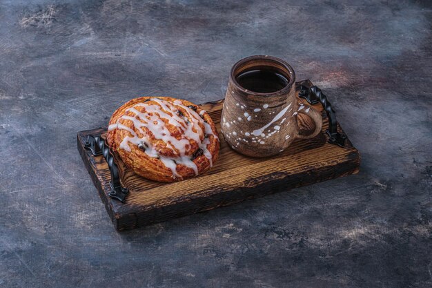 Sweet pastry with cup of coffee on wooden board