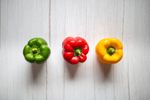 Sweet pepper, red, green, yellow paprika, on wooden background.