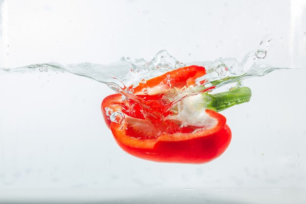 Sweet pepper in water splashes, red sweet pepper on white