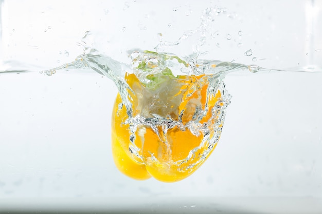 Photo sweet pepper in the water splashes, the yellow sweet pepper on white