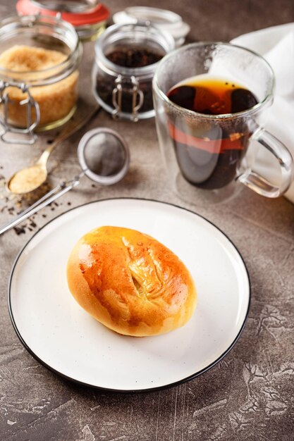 Sweet pies or buns made from yeast dough on platter and glass of tea
