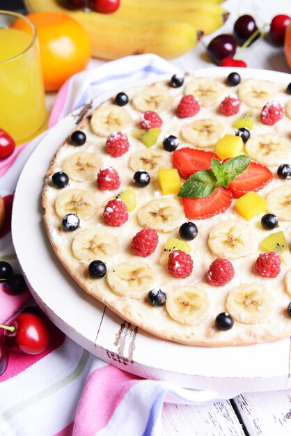 Sweet pizza with fruits on table closeup