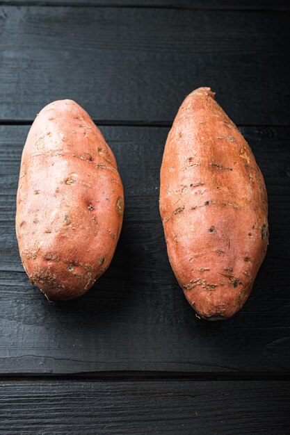 Sweet potato or batat, on black wooden background.