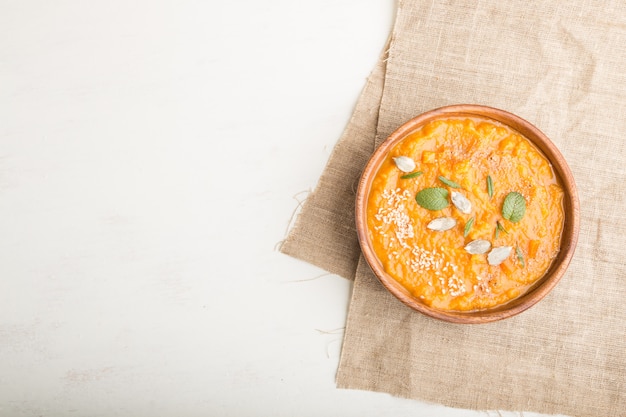 Sweet potato or batata soup in a wooden bowl on white background