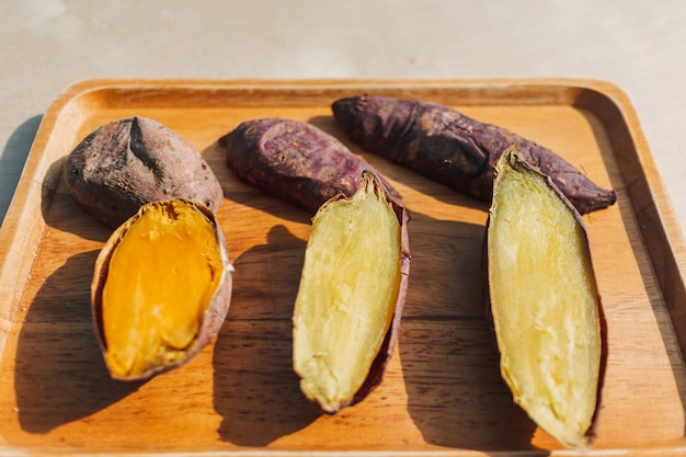 Sweet potato cut into half on wooden plate