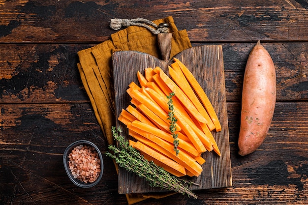 Sweet potatoes on a cutting board fresh batata french fries ready for cooking Wooden background Top view