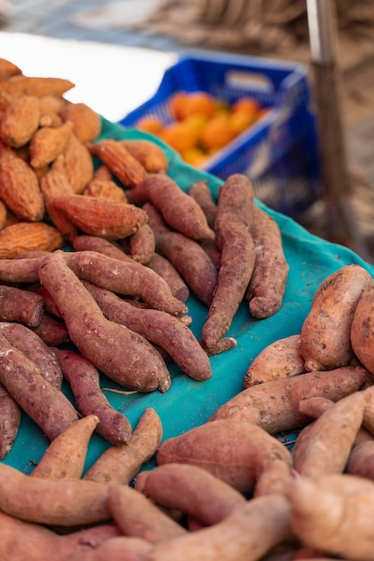 Sweet potatoes named batata on counter market on background of lemons.