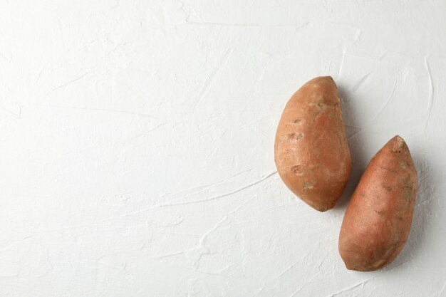 Sweet potatoes on white surface