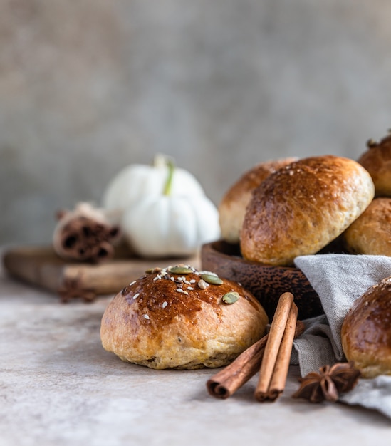 Sweet pumpkin buns with cinnamon and anise, light concrete background. Selective focus.