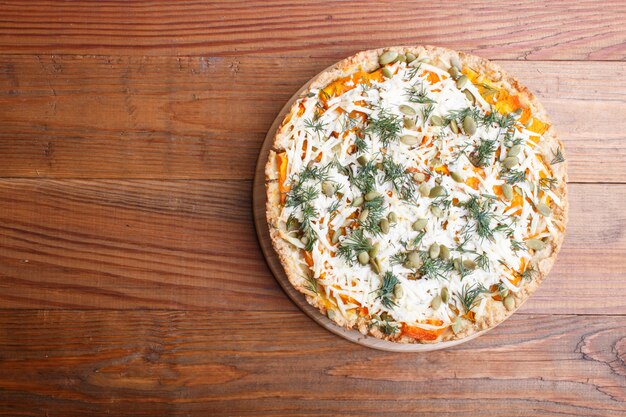 Sweet pumpkin pie with cheese and dill on brown wooden background.