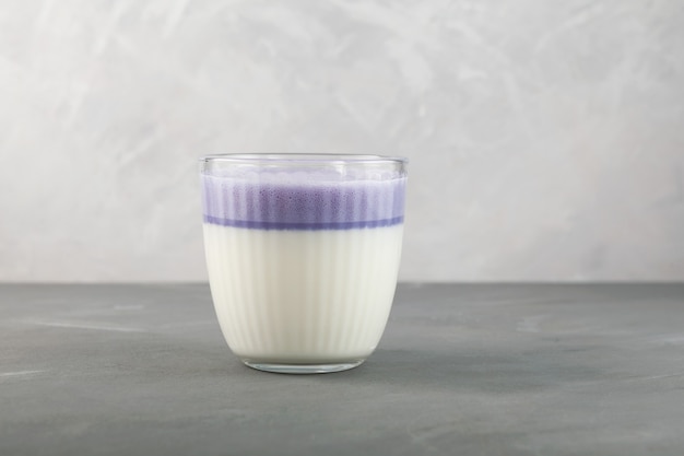 Фото Сладкий фиолетовый картофельный латте в стакане на сером фоне корейский здоровый освежающий напиток
