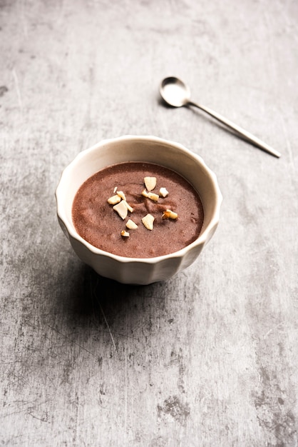 Photo sweet ragi malt or healthy ragi porridge in a bowl garnished with crushed dry fruits