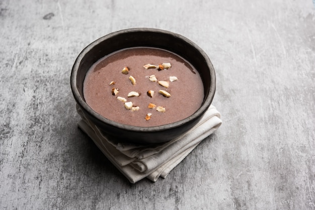 Photo sweet ragi malt or healthy ragi porridge in a bowl garnished with crushed dry fruits