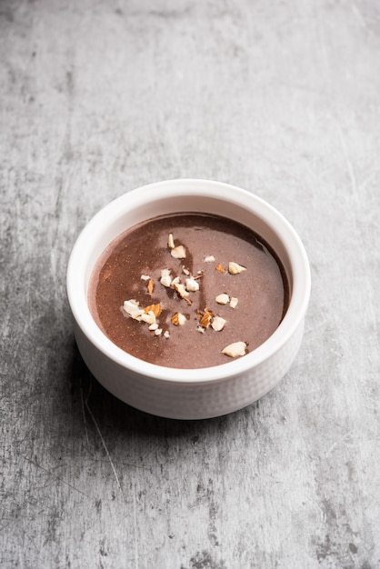 Photo sweet ragi malt or healthy ragi porridge in a bowl garnished with crushed dry fruits