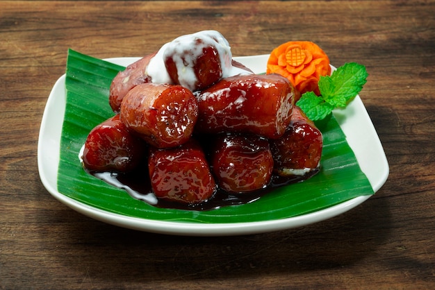 코코넛 밀크와 함께 달콤한 빨간 바나나 나무 배경에 접시에 새겨진 당근 꽃으로 장식