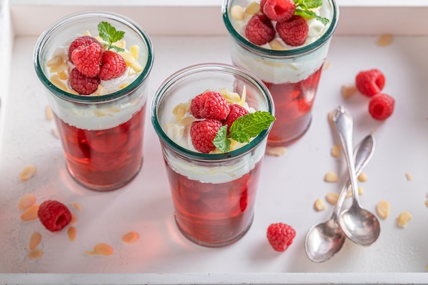 Sweet red jelly with raw raspberries and whipped cream