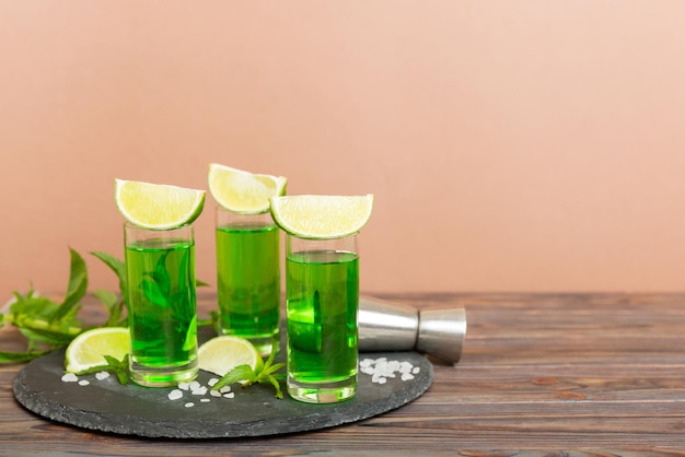 Sweet refreshing mint liqueur with ice and mint leaves on table
background shots with lime slice and mint flat lay