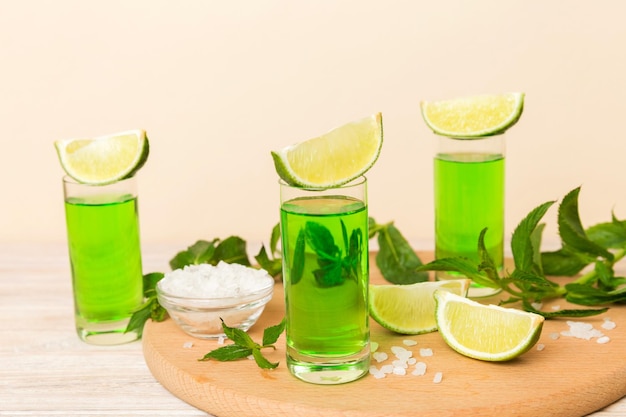 Sweet refreshing mint liqueur with ice and mint leaves on table\
background shots with lime slice and mint flat lay