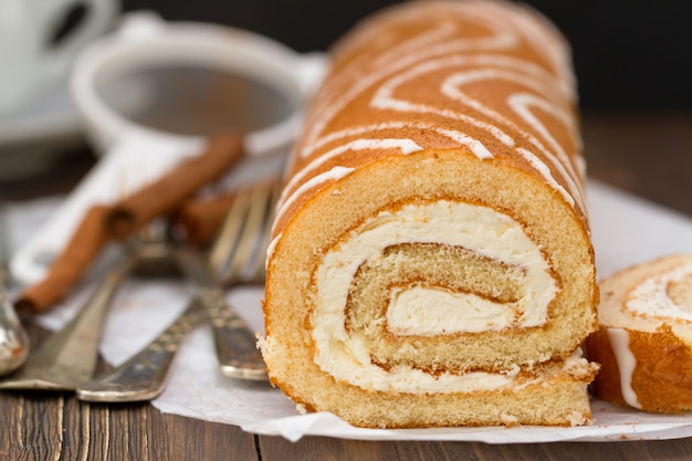 Sweet roll in white paper on brown background