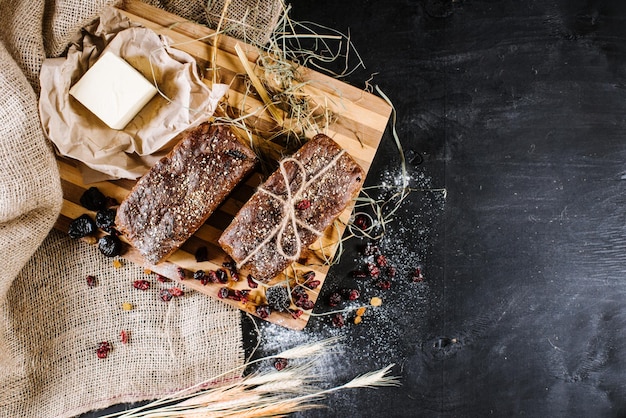 Sweet rye bread with different ingredients on black wooden background