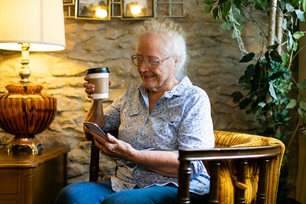 Photo sweet senior woman using her phone at a cafe