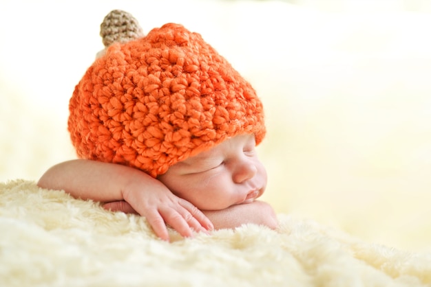 Sweet sleeping newborn baby wearing pumpkin hat