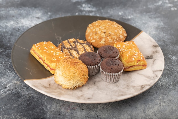 Sweet snacks in plate placed on a stone table .