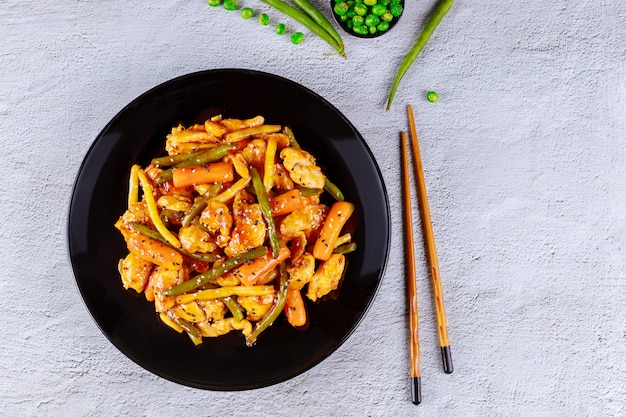 Photo sweet and spisy chicken and vegetable in black plate