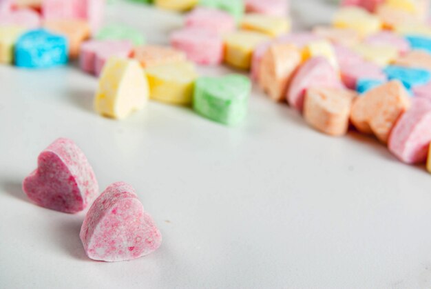 Photo sweet sugar candy on dorm of hearts on white marble table