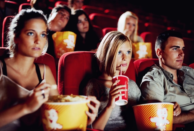 Photo sweet suspense friends sitting with refreshments and popcorn enjoying a movie together