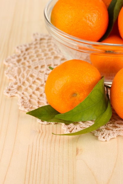 Sweet tangerines with leaves on wooden background