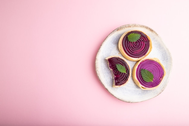 Sweet tartlets with jelly and milk cream on a pastel pink background. top view, flat lay, copy space.