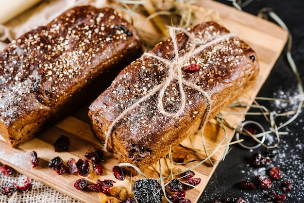 Sweet and tasty bread and wheat on black wooden background