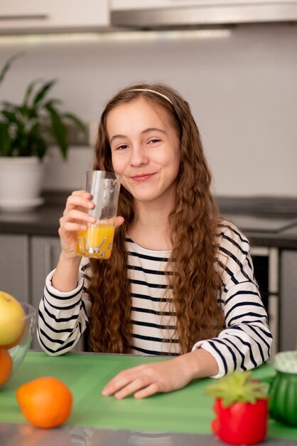 甘い10代の少女はオレンジ色の新鮮な健康的な食事家族の新鮮な果物を飲みます