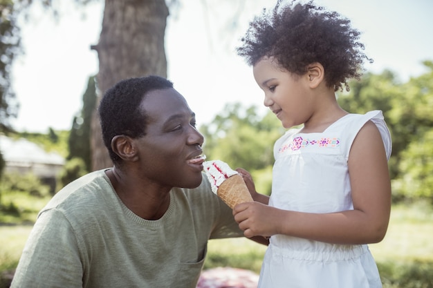 Sweet time. curly-haired cute kid eating ice-cream and spending
time with dad