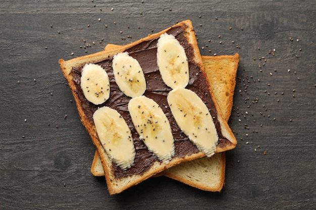 Sweet toast with banana on wooden background