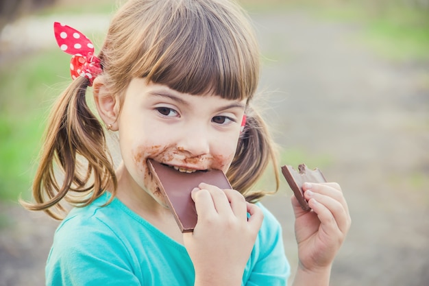 A sweet-toothed child eats chocolate. Selective focus.