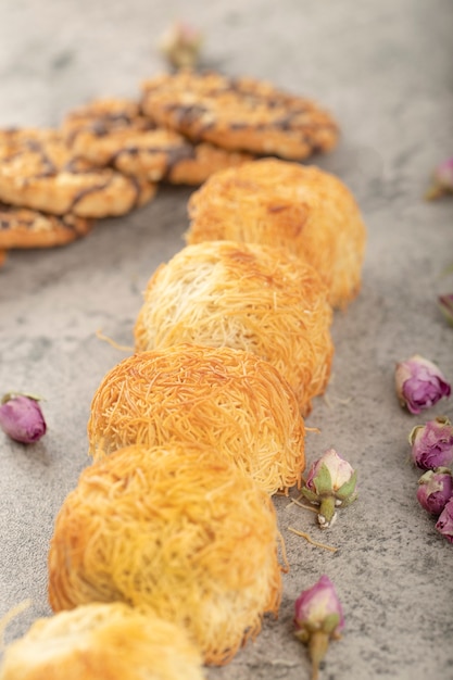 Sweet turkish dessert and oatmeal cookies with dried roses on stone.