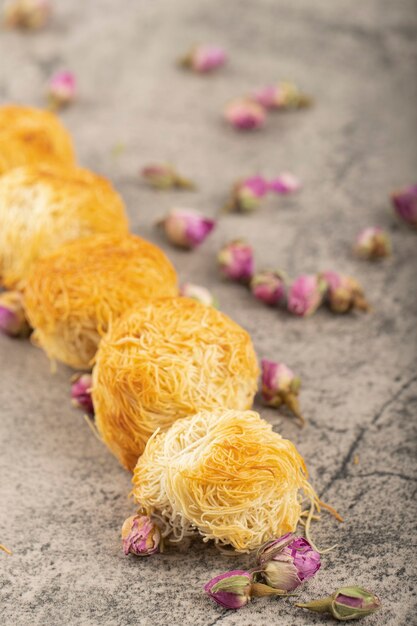 Sweet turkish dessert with dried roses on stone surface