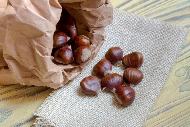 木製のテーブルのクローズアップの紙袋に甘い有用な食用栗カスタネアサティバ