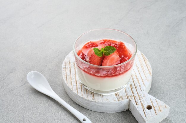 Sweet vanilla silky pudding dessert with strawberry sauce sliced fresh strawberries and mint leaf