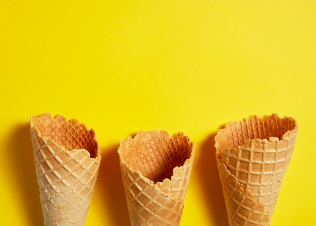 Foto cono gelato cialda dolce su sfondo giallo, estate e concetto vuoto. vista dall'alto. lay piatto